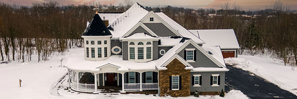 Jenkins Township home exterior, snow covered with clean asphalt driveway leading to a detached garage