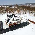 Aerial view of Jenkins Township home rear exterior, snow covered. With detached garage.