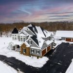 Arial corner view of Jenkins Township home exterior, snow covered. Seeing attached and detached garage doors.